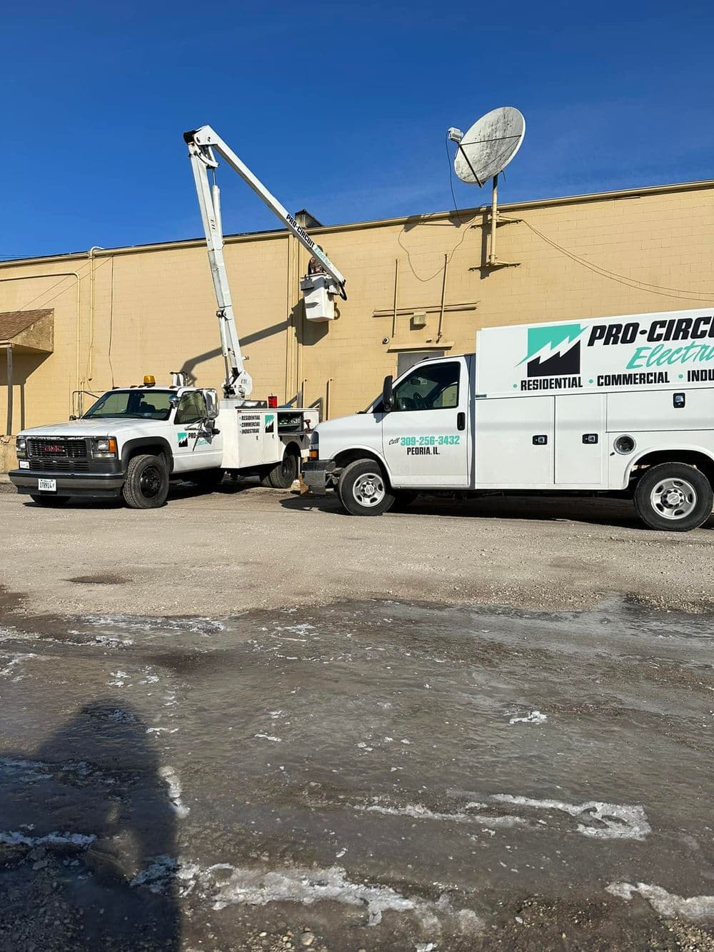 Pro Circuit Electric trucks with crane and service van parked outside a commercial building.